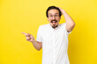 © luismolinero - Young caucasian man isolated on yellow background surprised and pointing finger to the side