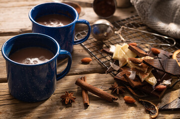 Stylish composition - two blue cups of coffee, pieces of chocolate, cinnamon sticks, almonds on a wooden background. Lots of objects. Restaurant, hotel, cafe, menu design. Country style.