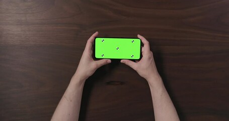 Sticker - Top view slow motion man hand show smartphone with green screen over black walnut wood table