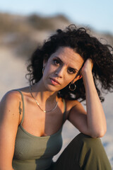 Wall Mural - Vertical shot of a Spanish curly female posing on the sand