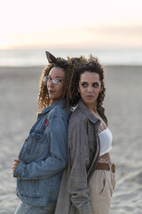 Vertical shot of a pair of young friends having fun and posing on a cold beach