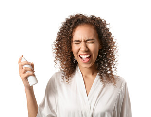 Young African-American woman spraying her hair on white background