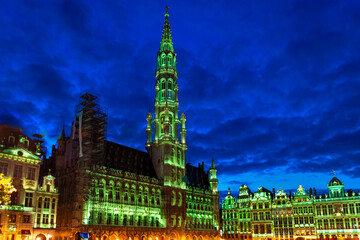 Wall Mural - The Grand Place or Grote Markt, the central square of Brussels Belgium, illuminated with green lights as tourist enjoy the evening.