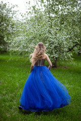  blonde girl in a blue dress in an apple orchard