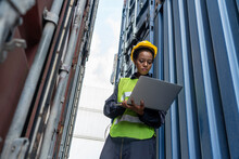 Young African American Woman Worker At Overseas Shipping Container Yard . Logistics Supply Chain Management And International Goods Export Concept .