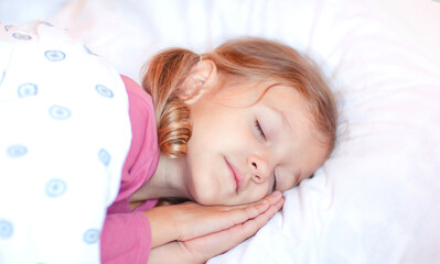 A little girl is sleeping with her hands under her head
