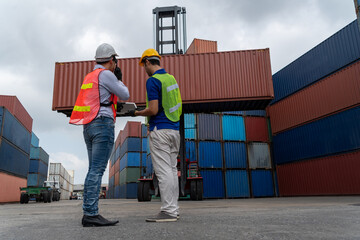 Wall Mural - Industrial worker works with co-worker at overseas shipping container yard . Logistics supply chain management and international goods export concept .