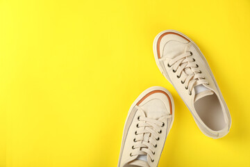 Wall Mural - Pair of beige sneakers on yellow background