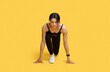 Sprint concept. Young african american female athlete in starting position ready for running, yellow background
