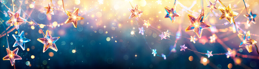 Wall Mural - christmas stars with golden lights hanging in blue background - string with abstract defocused bokeh