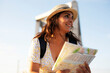 © JustLife - Happy young woman with a city map travelling. Young beautiful female traveler, standing on the street and looking at the map...