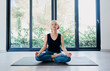 © luengo_ua - Yoga at home Senior woman in lotus pose sitting on the mat against big window. Concept of calm and meditation.