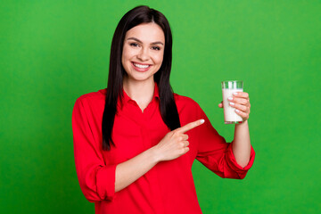 Wall Mural - Photo of optimistic brunette young lady point milk wear red shirt isolated on green color background