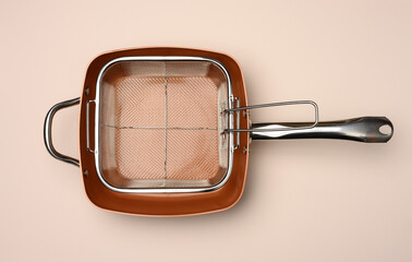 Wall Mural - empty copper deep frying pan with grill grate on beige background. View from above