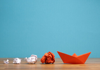 Wall Mural - Teamwork business concept with crumpled paper and a paper boat on a wooden office table