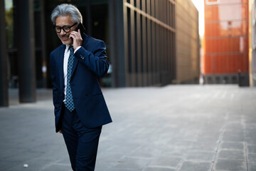 Wall Mural - Senior businessman outdoors. Middle-aged businessman talking to the phone