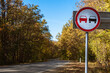 © VeNN - No overtaking sign against the backdrop of a country road and an autumn forest. The concept of road safety.