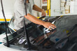 Car specialist applying tinting foil on a car window in auto service.