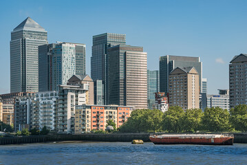  Scenic view on a sunny day with blue skies on office buildings, skyscrapers, River Thames, yacht, marina and residential buildings in the business district of London, UK.