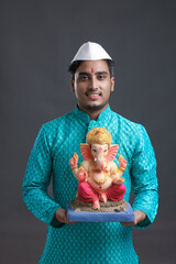 Young indian man with lord ganesha sclupture. celebrate ganesha festival.