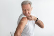 Mature Man Posing After Coronavirus Vaccination Showing Arm, Gray Background