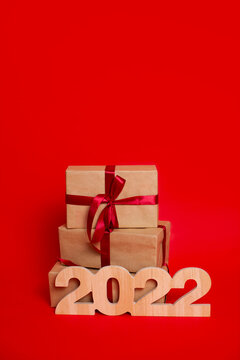 Merry Christmas and Happy New Year. Gift boxes and wooden numerals 2022 on a red background. A place for text.