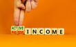 Passive or active income symbol. Businessman turns wooden cubes and changes words passive income to active income. Beautiful orange background, copy space. Business, passive or active income concept.