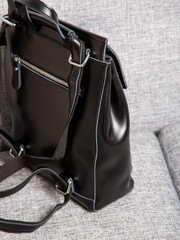 Black backpack bag with straps with zippers. bag for things, accessories and textbooks is in interior of apartment.