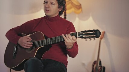 Wall Mural - Male musician playing acoustic guitar on the amplifier in retro vintage room.	
