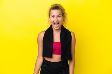 Wall Mural - Sport woman with towel isolated on yellow background with surprise facial expression