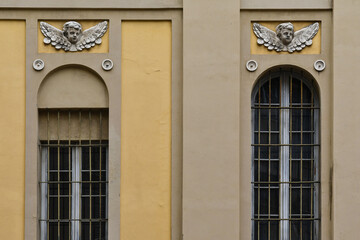 Canvas Print - Detail of the exterior of a church with high arched windows and bas-reliefs representing putti, Parma, Emilia-Romagna, Italy