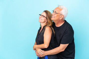 Wall Mural - Middle age couple isolated on blue background looking to the side