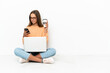 © luismolinero - Young woman with a laptop sitting on the floor holding coffee to take away and a mobile