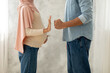 Domestic abuse concept. Muslim husband threatening pregnant wife with fist, woman showing stop gesture