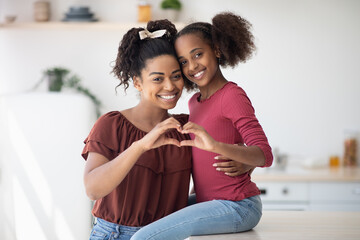 Wall Mural - Cute african american mother and daughter showing heart gesture