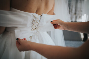 Poster - Closeup shot of a woman tying the wedding dress bow on the bride at a wedding in Sarajevo