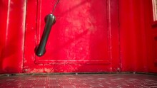 Black Handset Hanging In A Red Telephone Box. Footage With A British Phone Booth