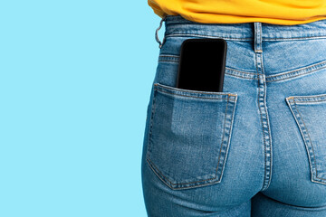 Poster - Cropped view of female having cellphone with blank screen in jeans pocket on blue studio background, mockup