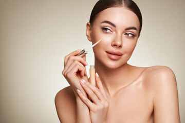 Wall Mural - portrait beautiful young woman with clean fresh skin. model with foundation makeup bottle. cosmetolo
