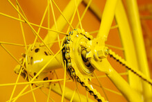 A Fragment Of The Rear Wheel Of A Bicycle With A Sprocket And Chain. Painted Frame And Details In Yellow. Close-up