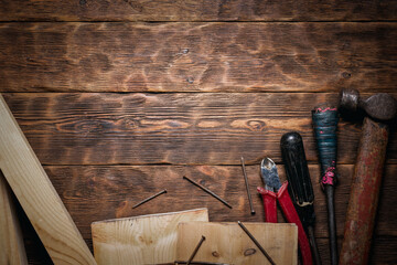 Wall Mural - Old hammer, screwdriver, pliers, wooden bars and nails on the wooden flat lay workbench background with copy space.