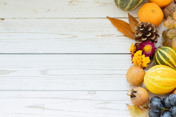 Wall Mural - Top view of white wooden background with fall fruits (pumpkins, grapes, tangerines, medlars, flowers, and leaves). The concept of thanksgiving and thankfulness to God Jesus Christ. Copy space.