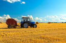 A Tractor Uses Trailed Bale Machine To Collect Straw In The Field And Make Round Large Bales. Agricultural Work, Baling, Baler, Hay Collection In The Summer Field.
