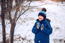 A Boy In A Blue Jacket And A Blue Hat Playing In The Snow