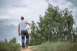 © Antonina Trushina - The father carries a little baby daughter in his arms. Without faces. Funny summer or spring photo. People with their backs.