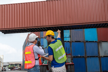 Wall Mural - Industrial worker works with co-worker at overseas shipping container yard . Logistics supply chain management and international goods export concept .