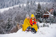 Children sledding, riding a sledge. Children son and daughter play in snow in winter. Outdoor kids fun for Christmas family vacation.