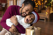 © fizkes - Overjoyed young African American father and small son have fun play together on Christmas at home. Happy biracial dad and little boy child feel playful laugh tickle enjoy New Year winter holidays.