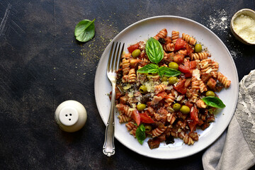 Wall Mural - Fusilli pasta with tomatoes, eggplants and olives. Top view with copy space.