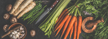 Various Vegetables And Kitchen Utensils On Dark Rustic Kitchen Table: Carrots, Garlic, Mushrooms, Celery And Parsnip. Healthy Lifestyle With Vegetarian Food. Top View. Banner.